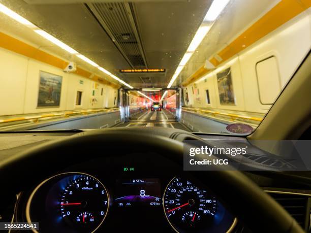 Car drives down inside the Eurotunnel train at night at Coquelles near Calais in France before being transported under the English Channel to...