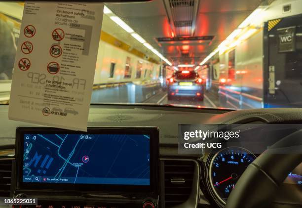 Car drives down inside the Eurotunnel train at night at Coquelles near Calais in France before being transported under the English Channel to...