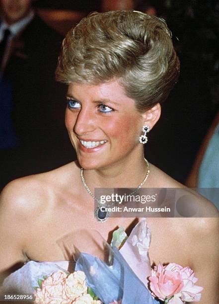 Diana, Princess of Wales, wearing a strapless blue chintz taffeta ball gown by Catherine Walker, smiles as she attends a dinner dance during the tour...