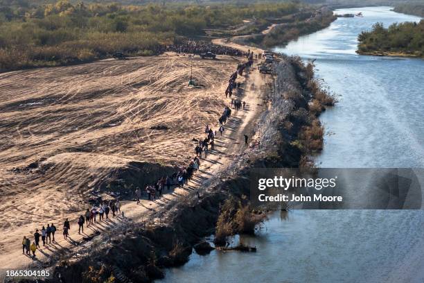 In this aerial view, A group of more than 1,000 immigrants walks towards a U.S. Border Patrol processing center after they crossed the Rio Grande...