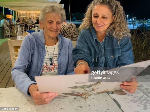 Malia, Crete, Greece, Europe, Women reading a menu. In a Greek restaurant, Malia, Crete.
