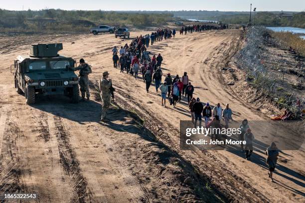 In this aerial view, Texas National Guard troops watch as a group of more than 1,000 migrants walk towards a U.S. Border Patrol field processing...