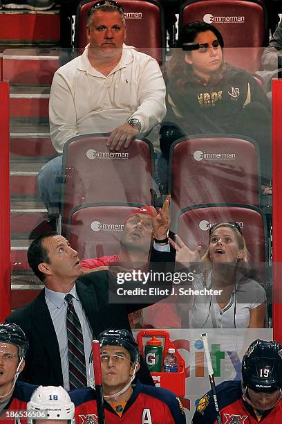 Head Coach Kevin Dineen of the Florida Panthers tosses a puck over the glass to fans during a break in the action against the Tampa Bay Lightning at...