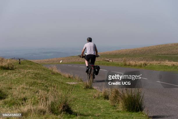 Dartmoor, Devon, England, UK, Man cycling on an empty road in Dartmoor national park in Devon, UK.