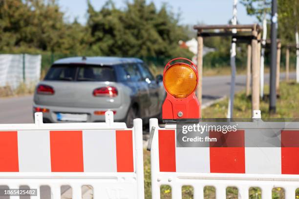 red warning light and barriers - road closed, with parking car - baustellenabsperrung stock-fotos und bilder
