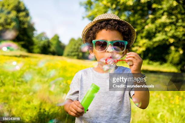 kind blasen blasen im park - child blowing bubbles stock-fotos und bilder