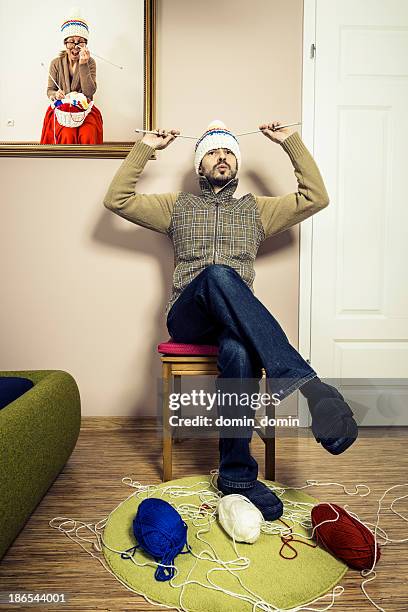 humorous, man sitting on chair and knitting winter cap, interior - man knitting stock pictures, royalty-free photos & images