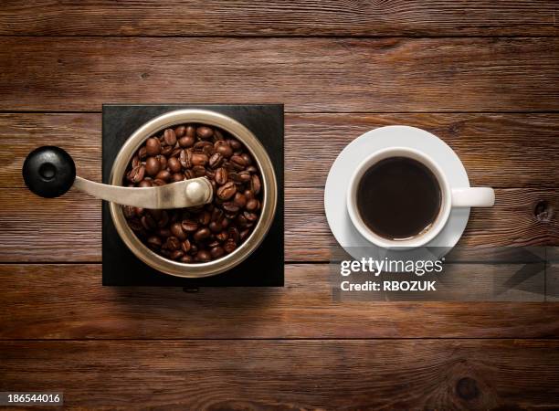 overhead shot of coffee cup and grinder on wooden background - grinder stockfoto's en -beelden