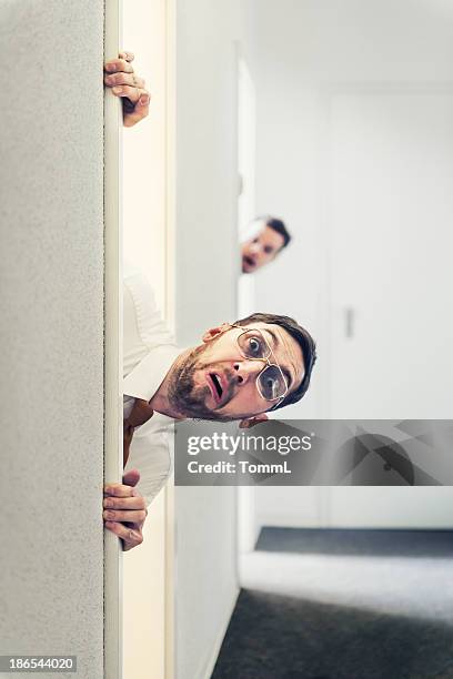 curious vintage business man looking around the corner - gluren stockfoto's en -beelden