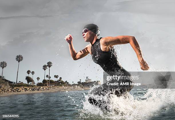 female triathlon athlete rushing out of the water - triathlon stockfoto's en -beelden