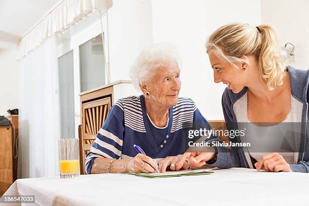 senior woman caregiver paperwork signing last will - erfenis stockfoto's en -beelden