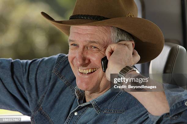 nahaufnahme von glücklichen farmer auf dem mobiltelefon - akubra hat stock-fotos und bilder