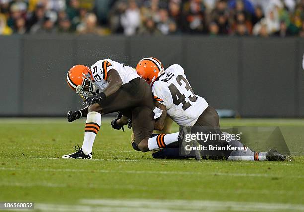 Defensive backs Tashaun Gipson and T.J. Ward of the Cleveland Browns tackle tight end Jermichael Finley of the Green Bay Packers after a 10-yard...