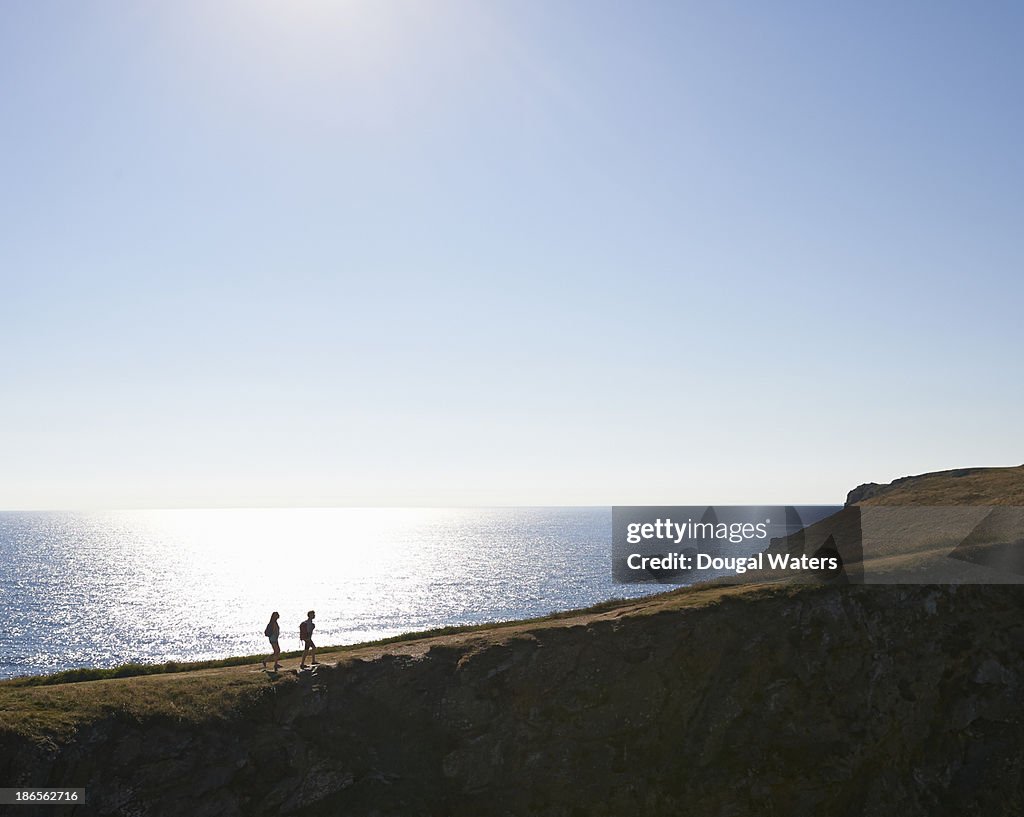 Wide view of couple hiking on UK coastline.