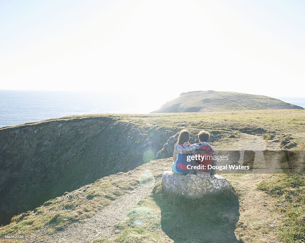 Couple sitting on a rock on a coastal path.
