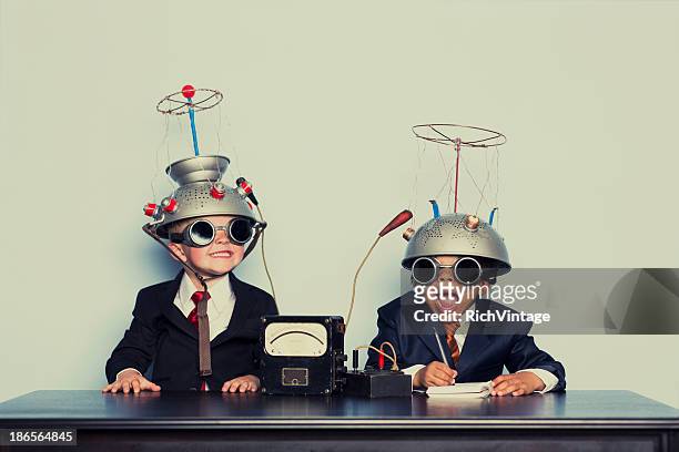 boys dressed as businessmen wearing mind reading helmets - humor stockfoto's en -beelden