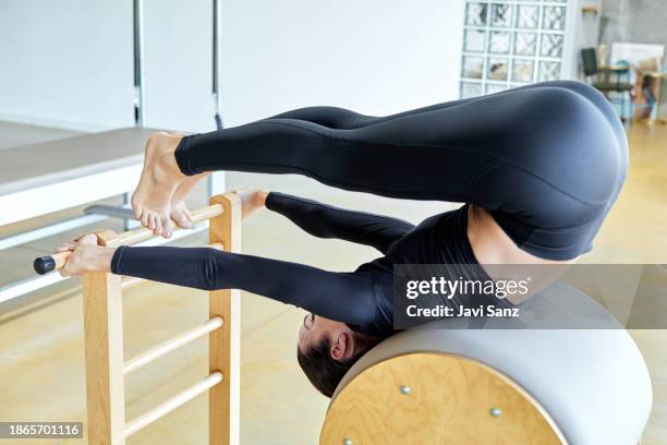 woman doing pilates and stretching exercises in a gym - reformer stock pictures, royalty-free photos & images