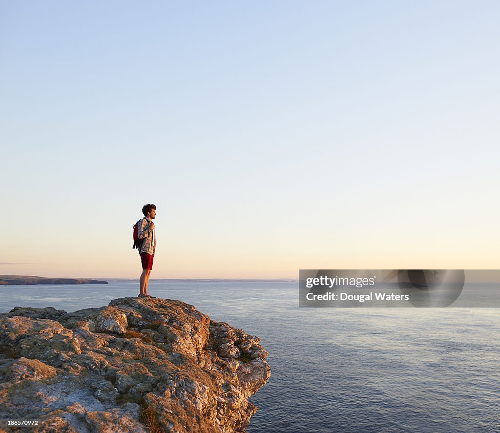 Hiker standing on rock and looking out to sea.