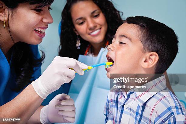 dentista insegnando spazzolino da denti utilizzare per/a figlio/a paziente - dentista bambini foto e immagini stock