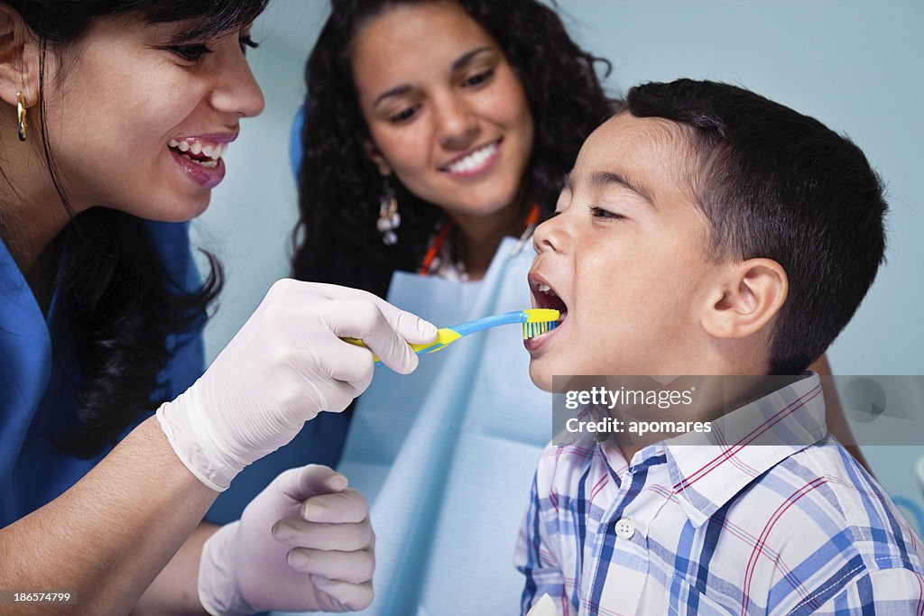 Dentist teaching toothbrush use to child patient