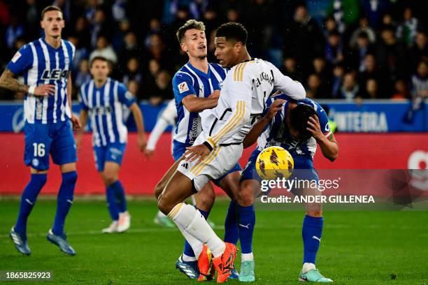 Real Madrid's English midfielder Jude Bellingham fights for the ball with Alaves' Spanish defender Antonio Blanco and Alaves' Spanish defender Ruben...