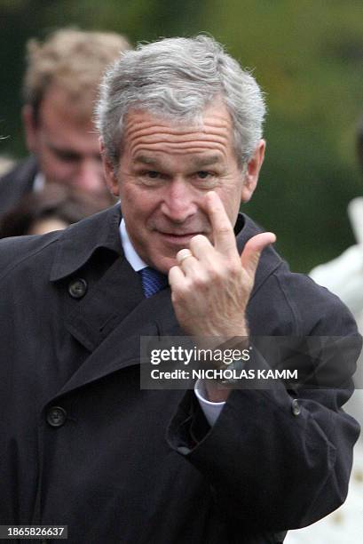 President George W. Bush motions to a staffer to come have her picture taken upon his return to the White House in Washington 07 October 2006 from...