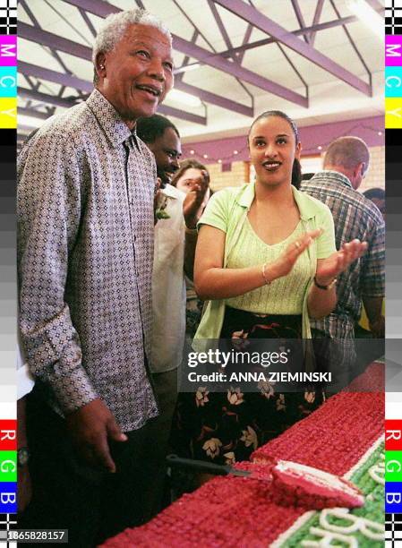 South African President Nelson Mandela cuts the first slice of a giant Christmas cake at the annual Christmas party which he throws for the children...