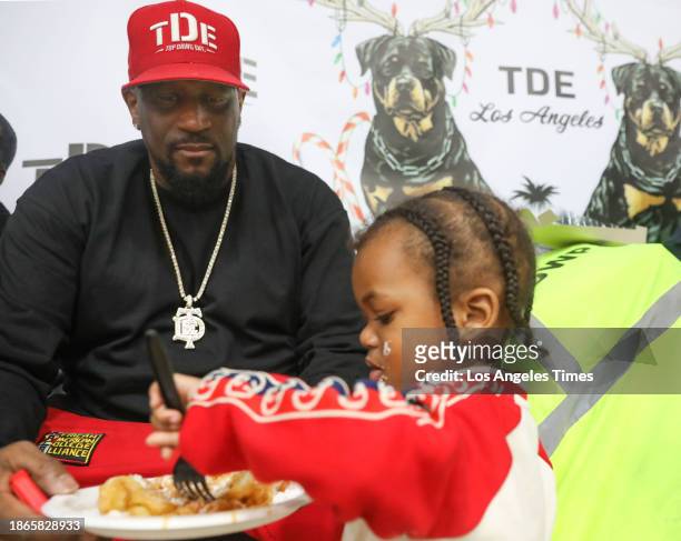 Watts, Los Angeles, CA Founder and CEO of Top Dawg Entertainment Anthony Tiffith gives funnel cake to Saint during a toy giveaway sponsored by Top...
