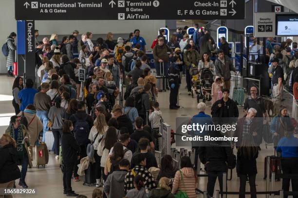 Travelers wait to go through security at San Francisco International Airport in San Francisco, California, US, on Thursday, Dec. 21, 2023. An...