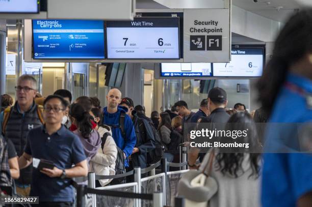 Travelers wait to go through security at San Francisco International Airport in San Francisco, California, US, on Thursday, Dec. 21, 2023. An...