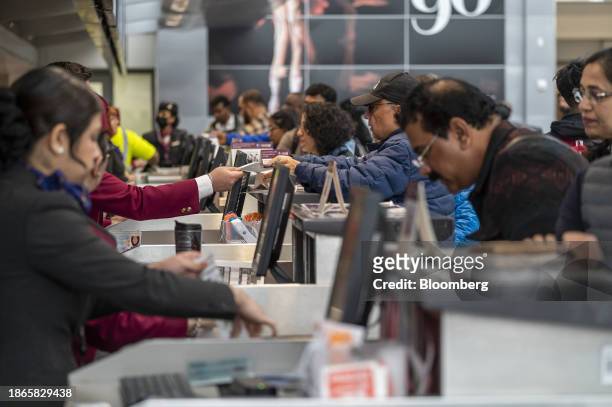Travelers check in at the Qatar Airways ticket counter at San Francisco International Airport in San Francisco, California, US, on Thursday, Dec. 21,...