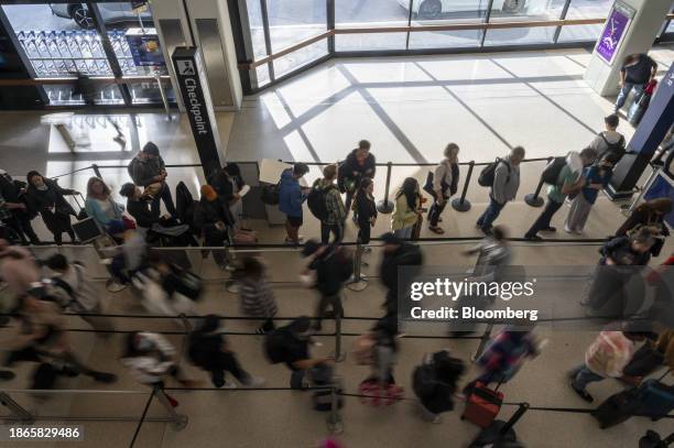 Travelers wait to go through security at San Francisco International Airport in San Francisco, California, US, on Thursday, Dec. 21, 2023. An...