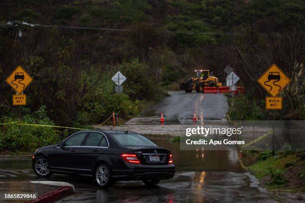 Driver does a detour after a creek overflows during heavy rains in Zuma Beach during heavy rains on December 21, 2023 in Malibu, California. Southern...
