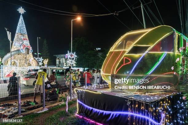 Commuters walk next to some Christmas decorations on the streets of Victoria Island in Lagos on December 18, 2023. Christmas and year-end...