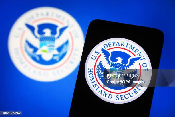 In this photo illustration, United States Department of Homeland Security logo is seen on a smartphone and on a pc screen.