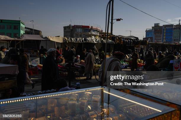 People walk and shop near jewelry stands in a street of Mandawi market, in central Kabul, Afghanistan, on November 23, 2023. Since their return to...