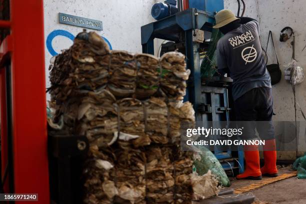 Staff member of the environmental organisation Sungai Watch uses a pressing machine to make bales of the trash collected by their river barriers for...