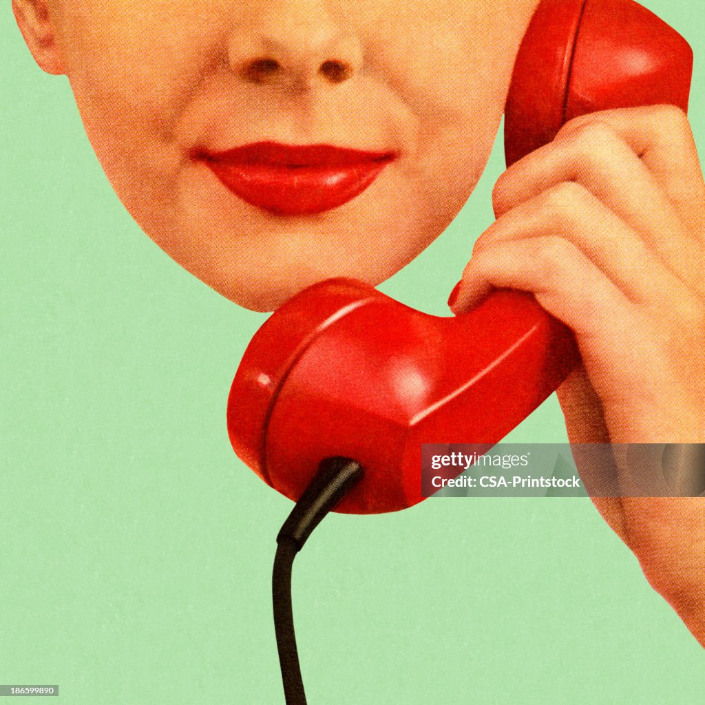Frau hält rotes Telefon an ihr Ohr