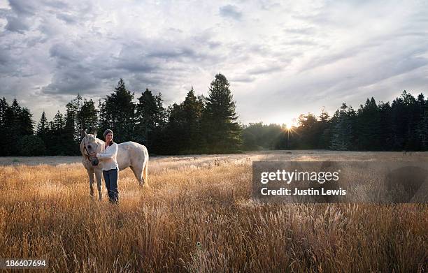 women with white horse in forest meadow at sunrise - 2013newwomen stock pictures, royalty-free photos & images