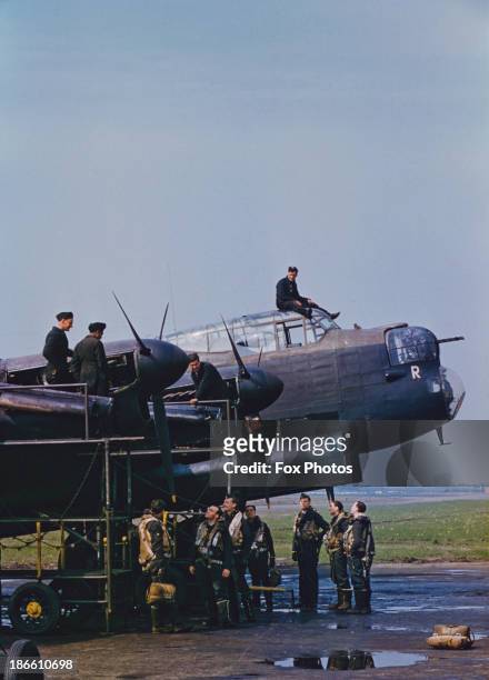 Mechanics servicing an RAF Avro Lancaster bomber as the aircrew look on, World War II, circa