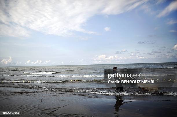 An Iranian fisherman pulls in his almost empty net after an unsuccessful fishing trip in the Caspian Sea in Koshk Estalkh village near the northern...