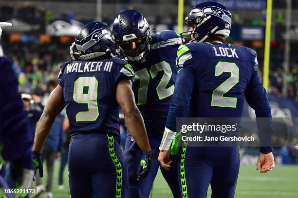 Kenneth Walker III celebrates with Drew Lock and Abraham Lucas of the Seattle Seahawks after a rushing touchdown in the third quarter at Lumen Field...