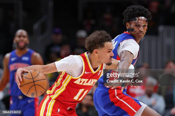 Trae Young of the Atlanta Hawks draws a foul from Ausar Thompson of the Detroit Pistons during the fourth quarter at State Farm Arena on December 18,...