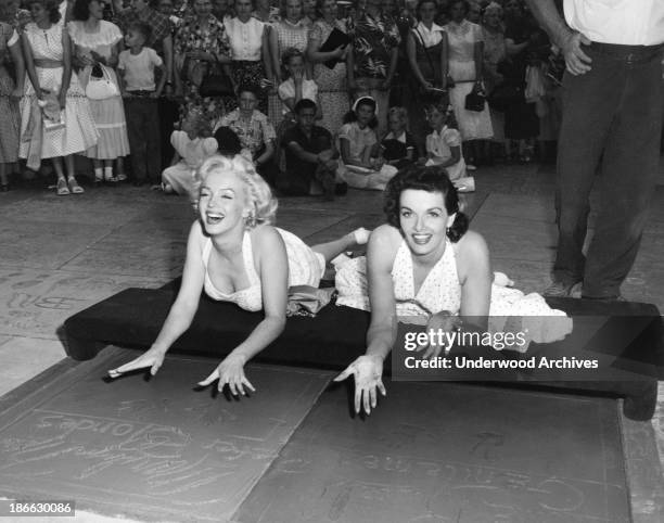 Actresses Marilyn Monroe {L) and Jane Russell put their handprints in wet cement at Grauman's Chinese Theater to promote their latest film,...
