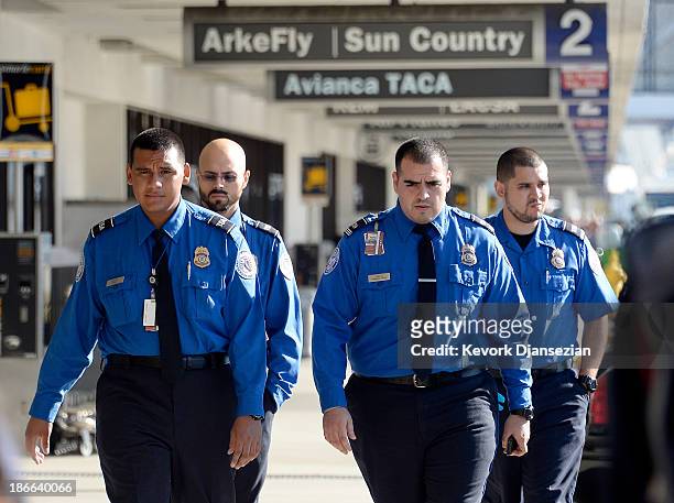 Transportation Security Administration agents walk on the departures level a day after a shooting that killed one Transportation Security...