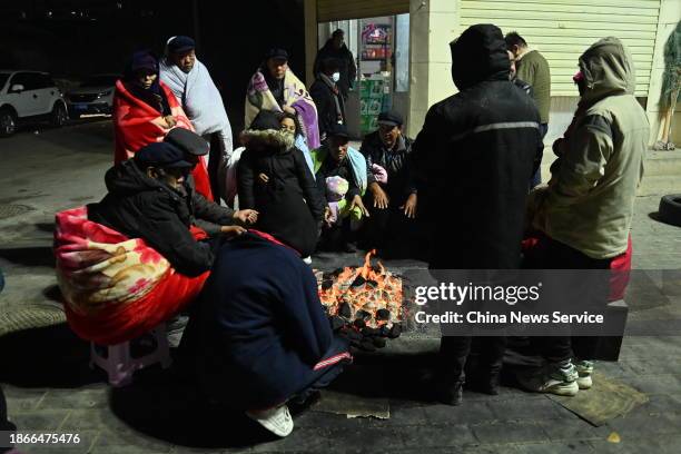 Residents gather around a fire to keep warm on a street after a 6.2-magnitude earthquake on December 19, 2023 in Jishishan Bonan, Dongxiang and Salar...