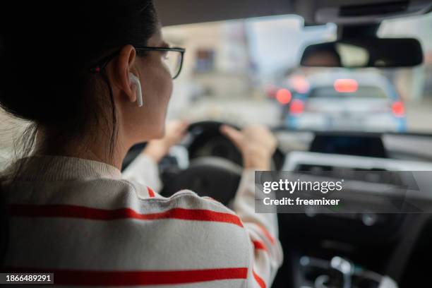 woman driving car in the city - in ear headphones stock pictures, royalty-free photos & images