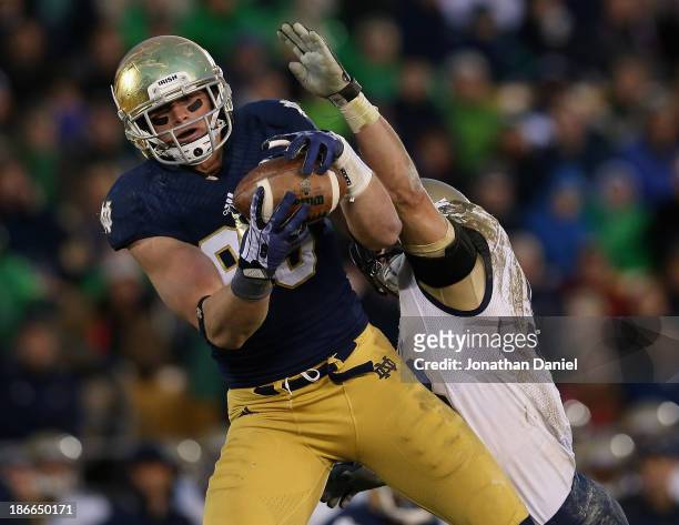Troy Niklas of the Notre Dame Fighting Irish catches a first down pass in front of Cody Peterson of the Navy Midshipmen at Notre Dame Stadium on...