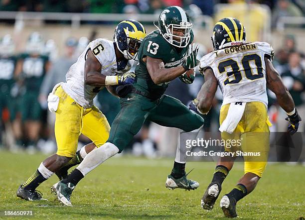Bennie Fowler of the Michigan State Spartans tries to avoid Raymon Taylor and Thomas Gordon of the Michigan Wolverines during the fourth quarter at...
