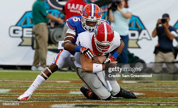 Aaron Murray of the Georgia Bulldogs is sacked by Loucheiz Purifoy of the Florida Gators during the game at EverBank Field on November 2, 2013 in...